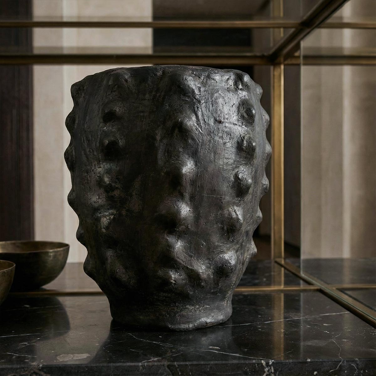 vaso Calice nero scolpito in ceramica nera lavorata a mano in contesto di arredo scuro.