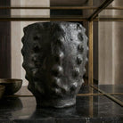 vaso Calice nero scolpito in ceramica nera lavorata a mano in contesto di arredo scuro.