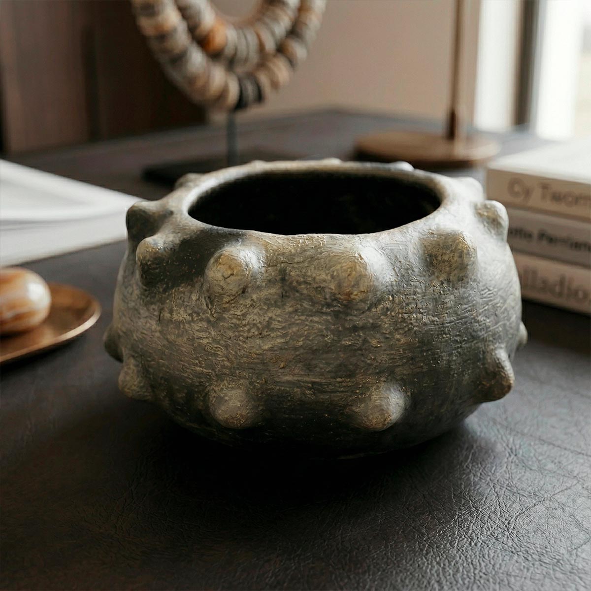 Ampia apertura superiore che rivela l'interno scuro della ciotola scultura di Mufida.