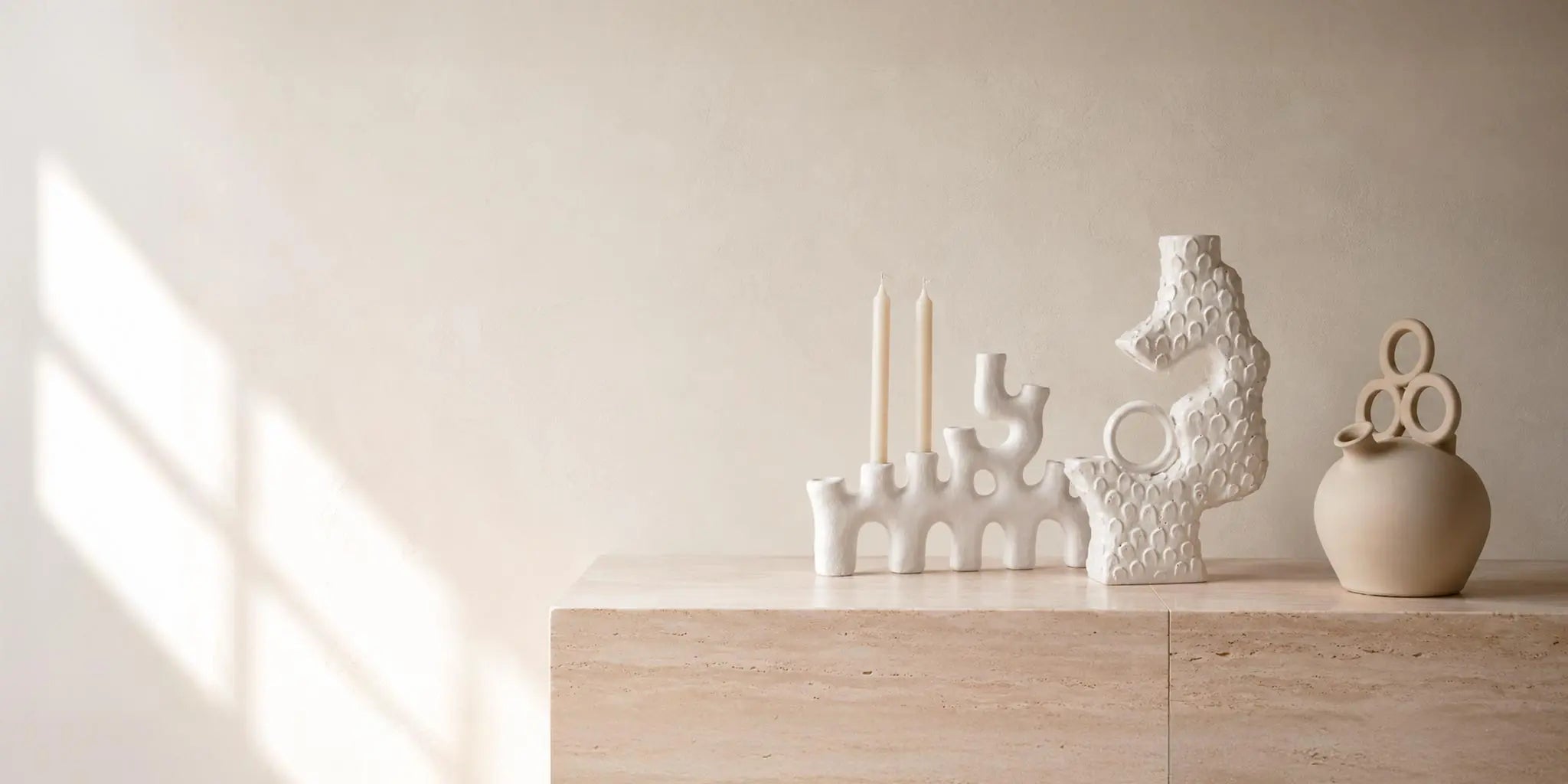 Oggetti di design bianchi e neutri con vasi e sculture artigianali in un interno contemporaneo