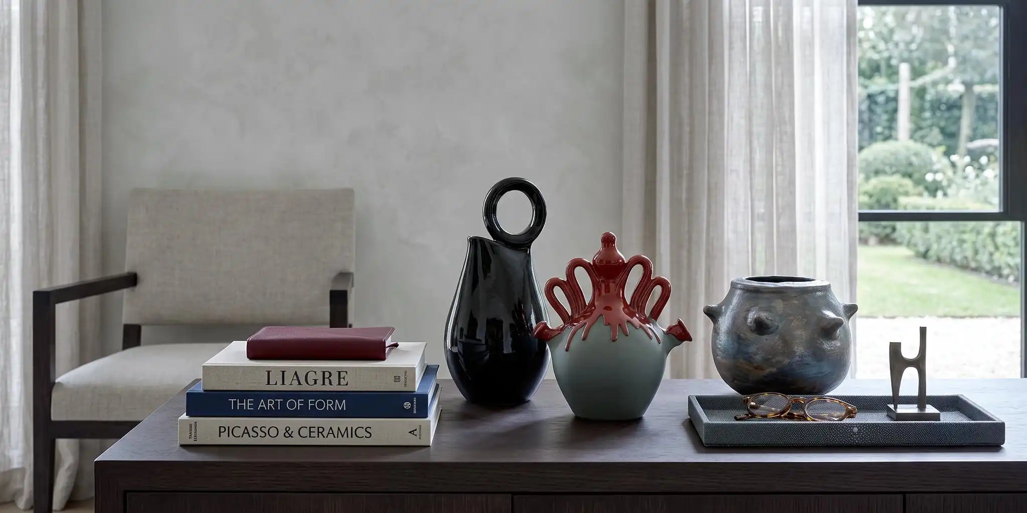 composizione di vasi in ceramica di diverse finiture e colori su credenza orizzontale in legno scuro in living di design stile liagre
