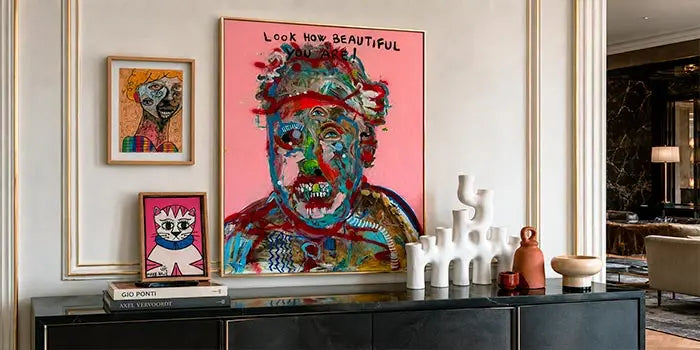 credenza in legno scuro, allestita con quadri e sculture con proporzioni e volumi e colori proporzionati.