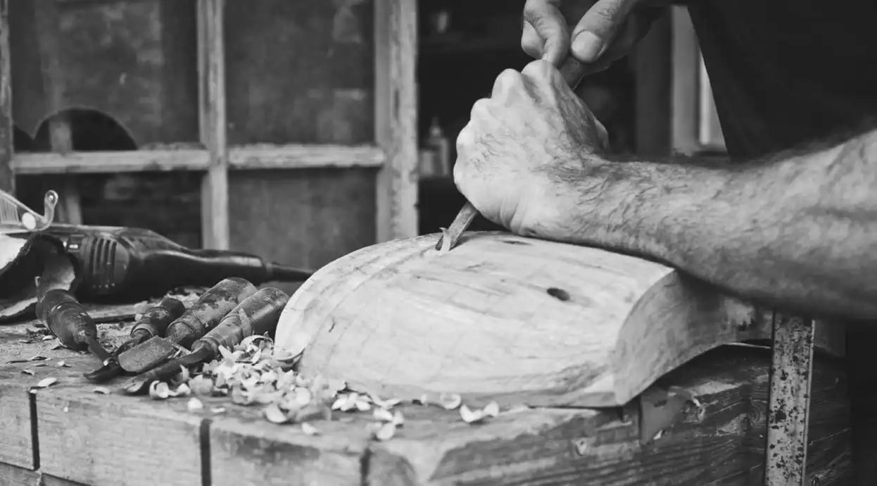 Dettaglio delle mani di Estebanland che utilizzano uno scalpello su un blocco di legno.