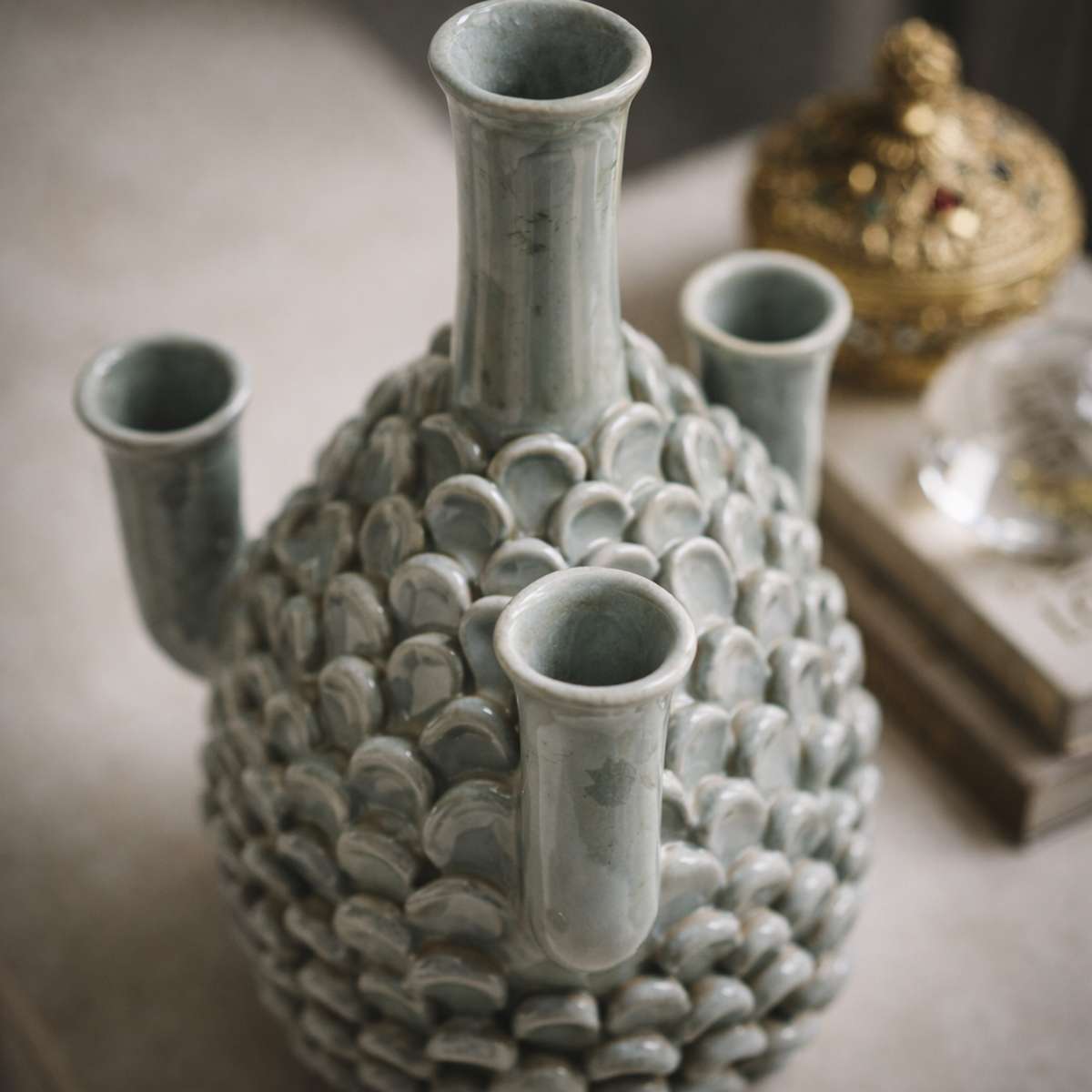 Vaso scultoreo a pigna in ceramica grigia su sfondo bianco neutro