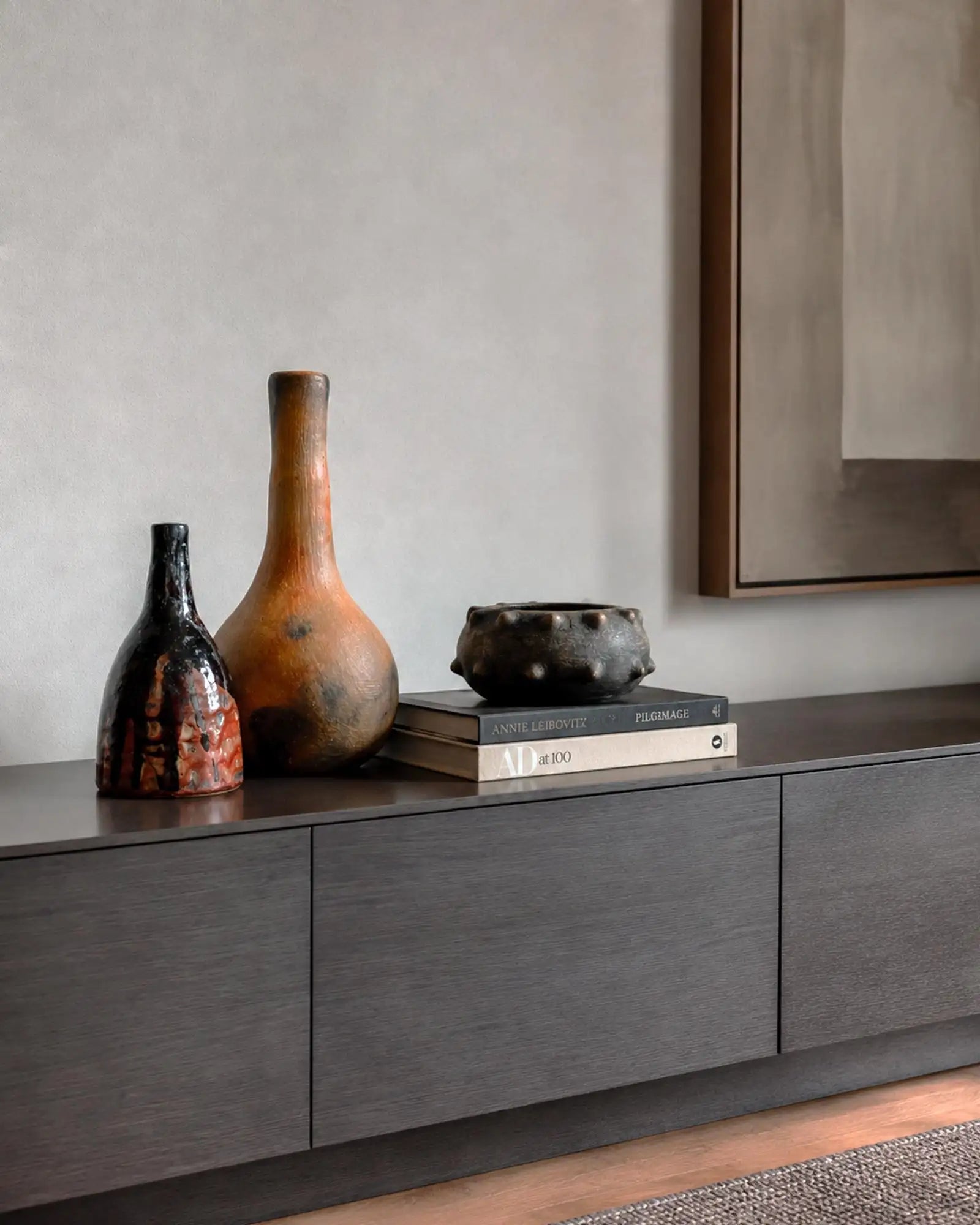 gruppo di vasi di diverse dimensioni e forme disposti su credenza orizzontale in legno scuro in interno di design