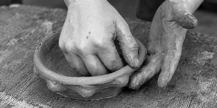 mani che lavorano l'argilla con tecnica antica senza uso del tornio, foto in bianco e nero