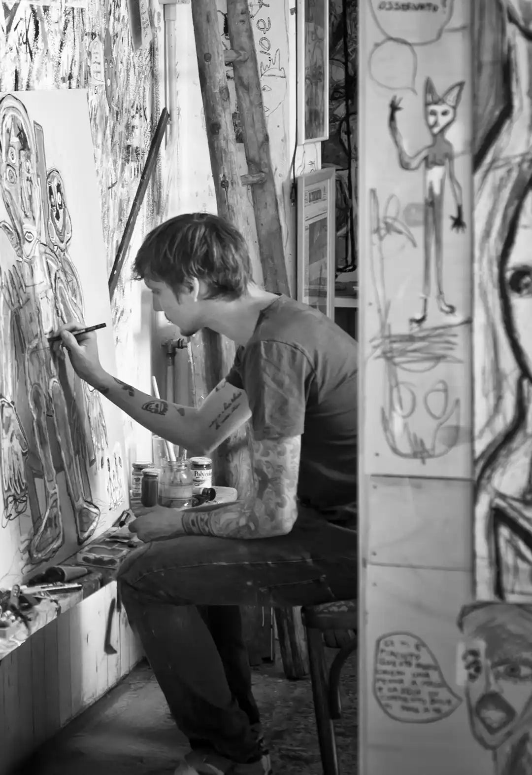 L'artista Massimiliano Precisi fotografato di profilo mentre dipinge su una tela nel suo studio.
