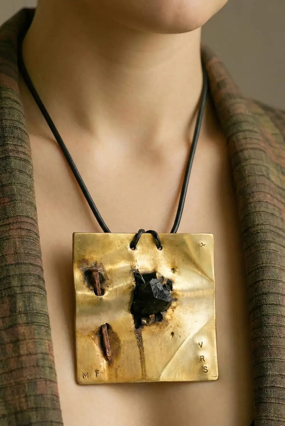dettaglio di una modella che indossa un monile in ottone, con pietra nera e chiodo corten, artigianale, della collezione monili nomad chic di vicodde