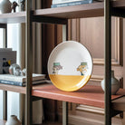 Il piatto maiolica dipinto accanto a un libro per mostrarne le dimensioni.