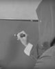 Video in bianco e nero che ritrae Uodi di spalle, incappucciato, mentre con un pennarello traccia la sua firma "UODI" in stile graffiti all'interno di un grande fumetto dipinto su una parete o una grande tela.