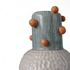 Mano che posiziona il vaso in ceramica rosso su una pila di libri d'arte.