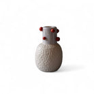 Il vaso in ceramica rosso esposto su una mensola bianca, che ne esalta il colore e la forma.