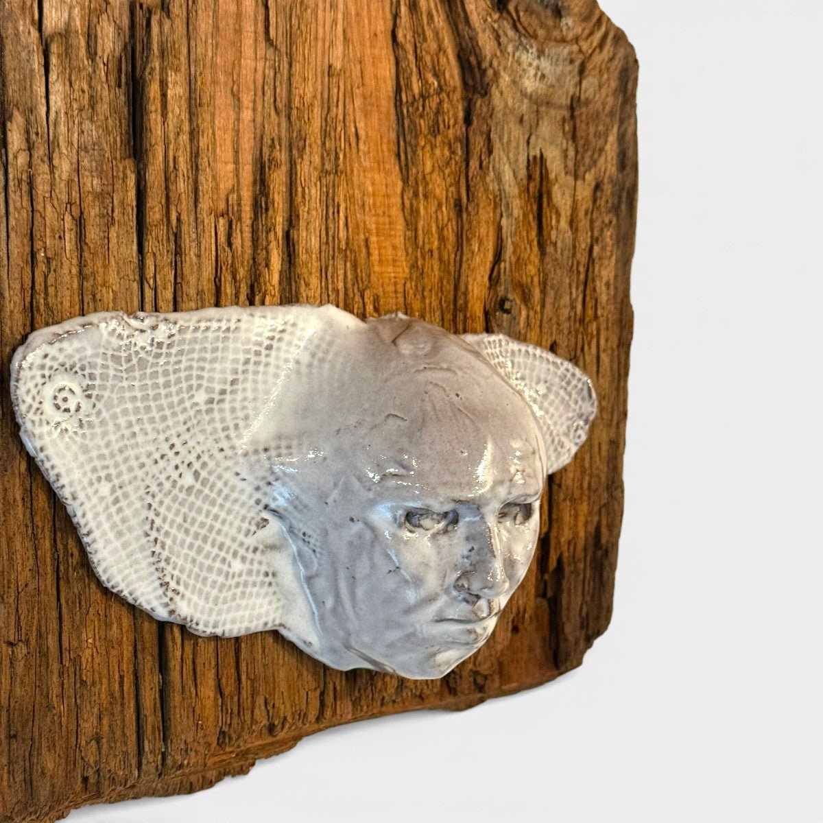 Sintesi visiva tra legno antico ossidato e volto scultoreo contemporaneo.