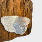 Sintesi visiva tra legno antico ossidato e volto scultoreo contemporaneo.