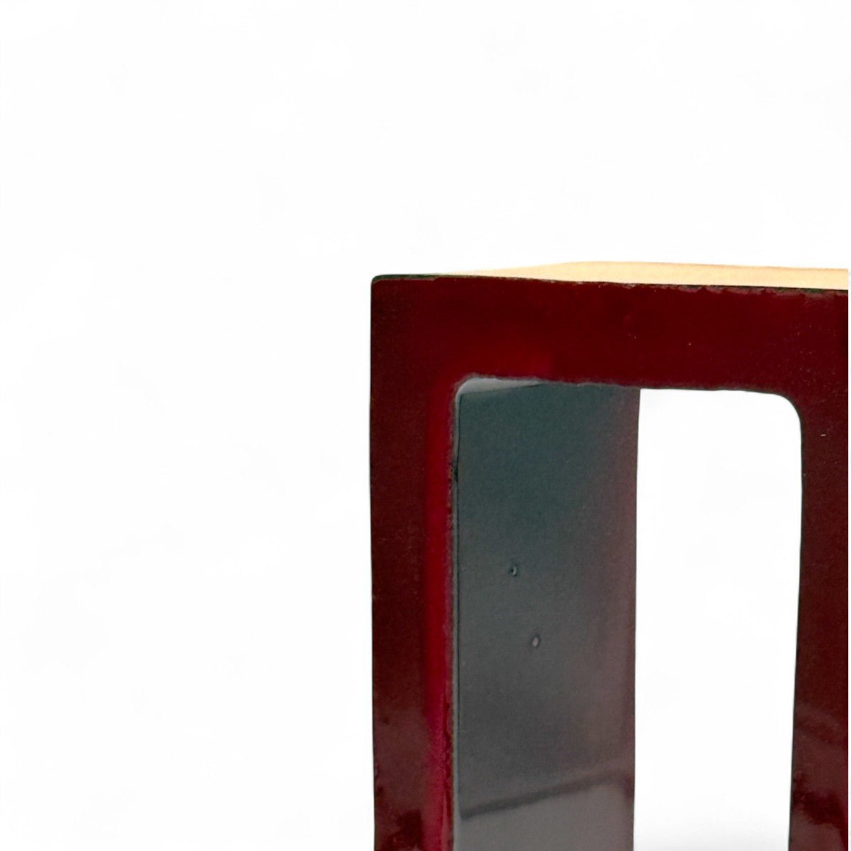 Primo piano dello smalto rosso rubino, liquido e riflettente, all'interno della scultura.