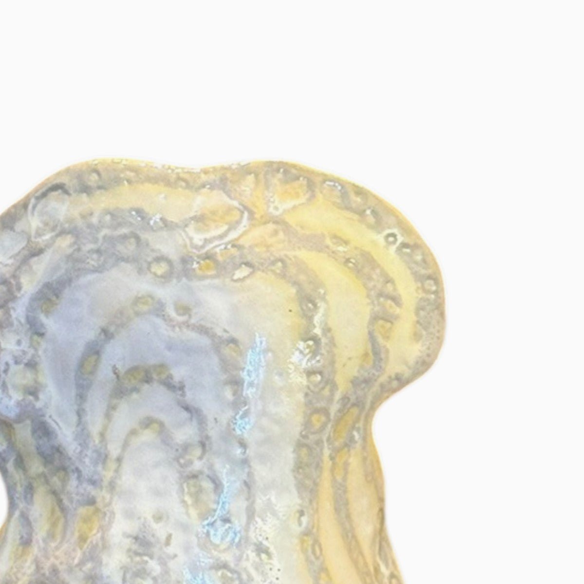 Riflessi di luce sulla superficie ceramica che esaltano le costolature verticali.