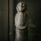 Braccia conserte modellate a rilievo che cingono il corpo cilindrico della statua decorativa di Sejnane.