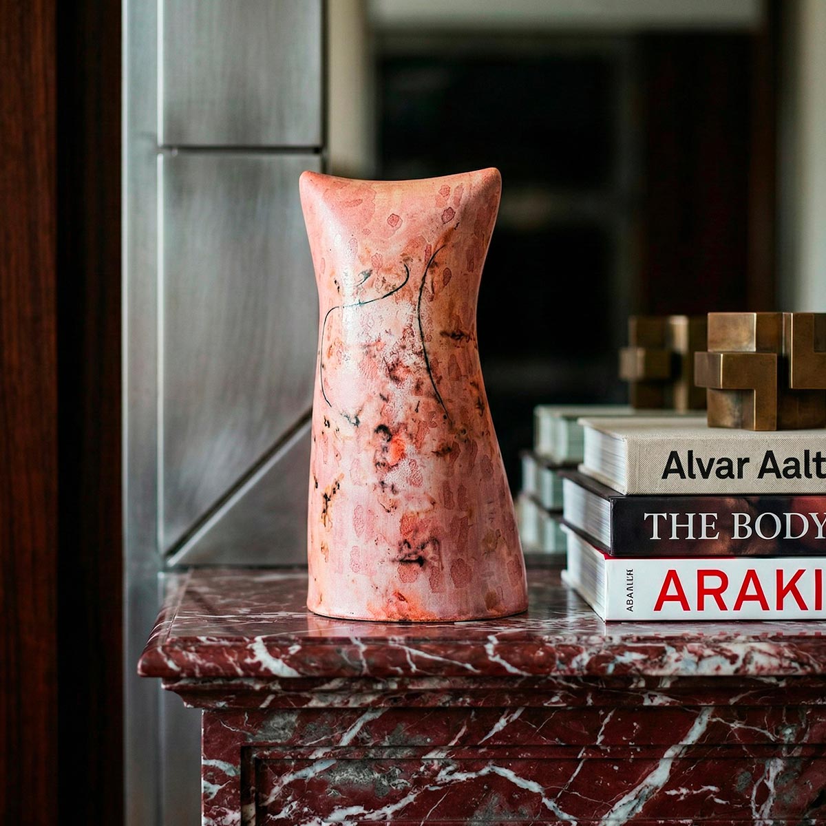 Scultura in ceramica calligrafica con sfumature rosa e segni grafici neri.