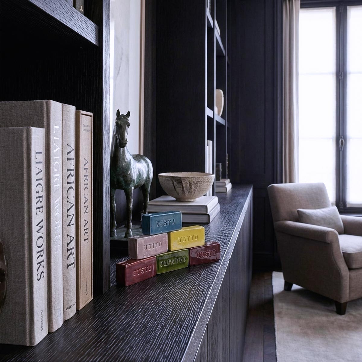 Le cinque Sculture dei Sensi disposte a piramide su unalibreria in legno scuro