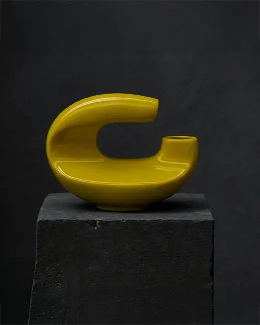 Scultura astratta di design in ceramica gialla lucida dalle forme curve e moderne per arredamento contemporaneo.
