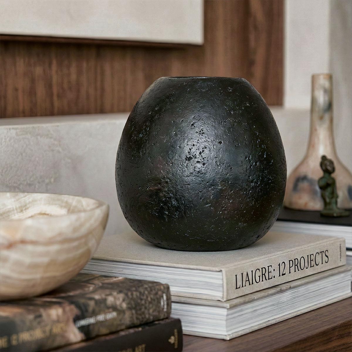 dettaglio del Vaso sferico nero artigianale su mensola in legno con libri.