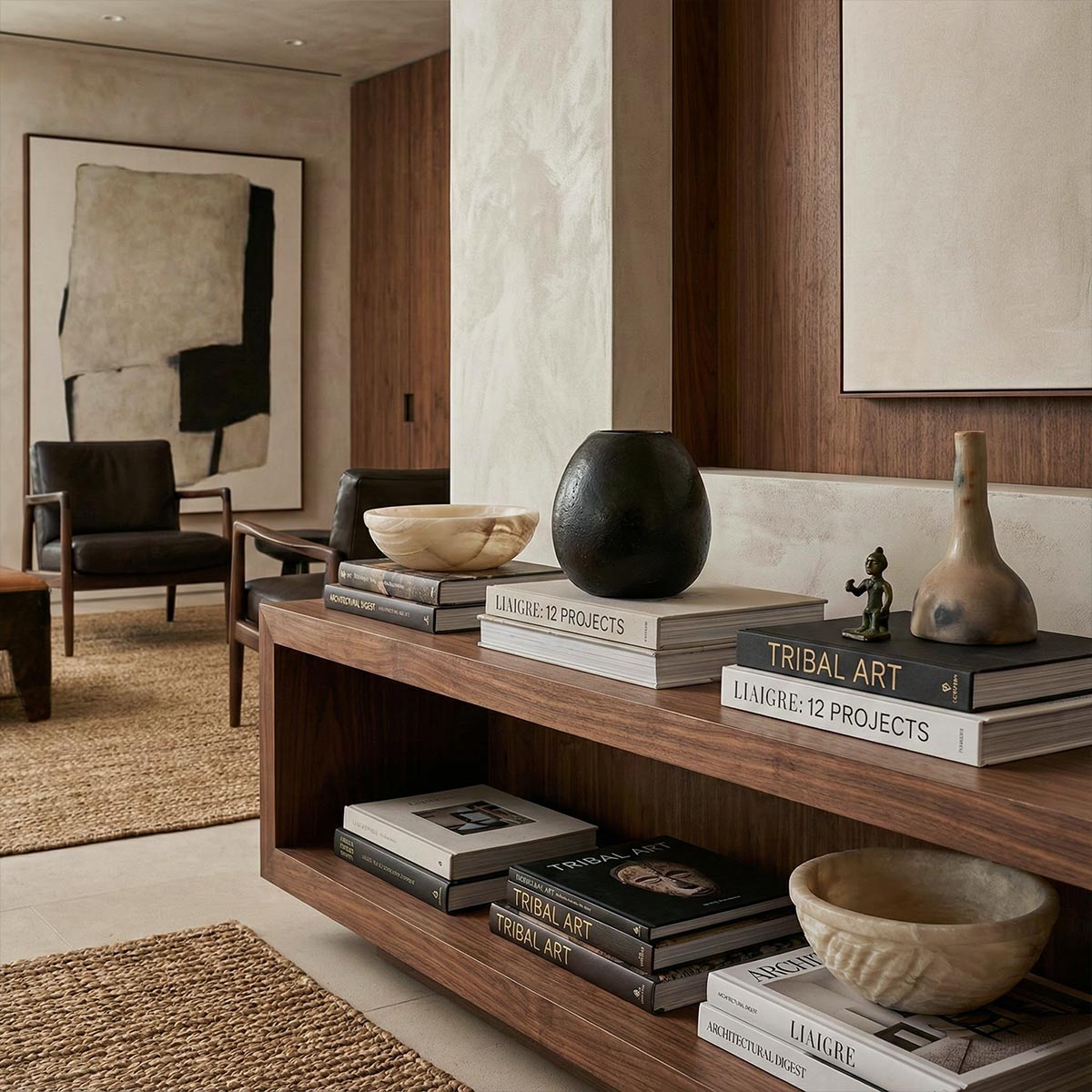 Vaso sferico nero su mensola in legno con libri.