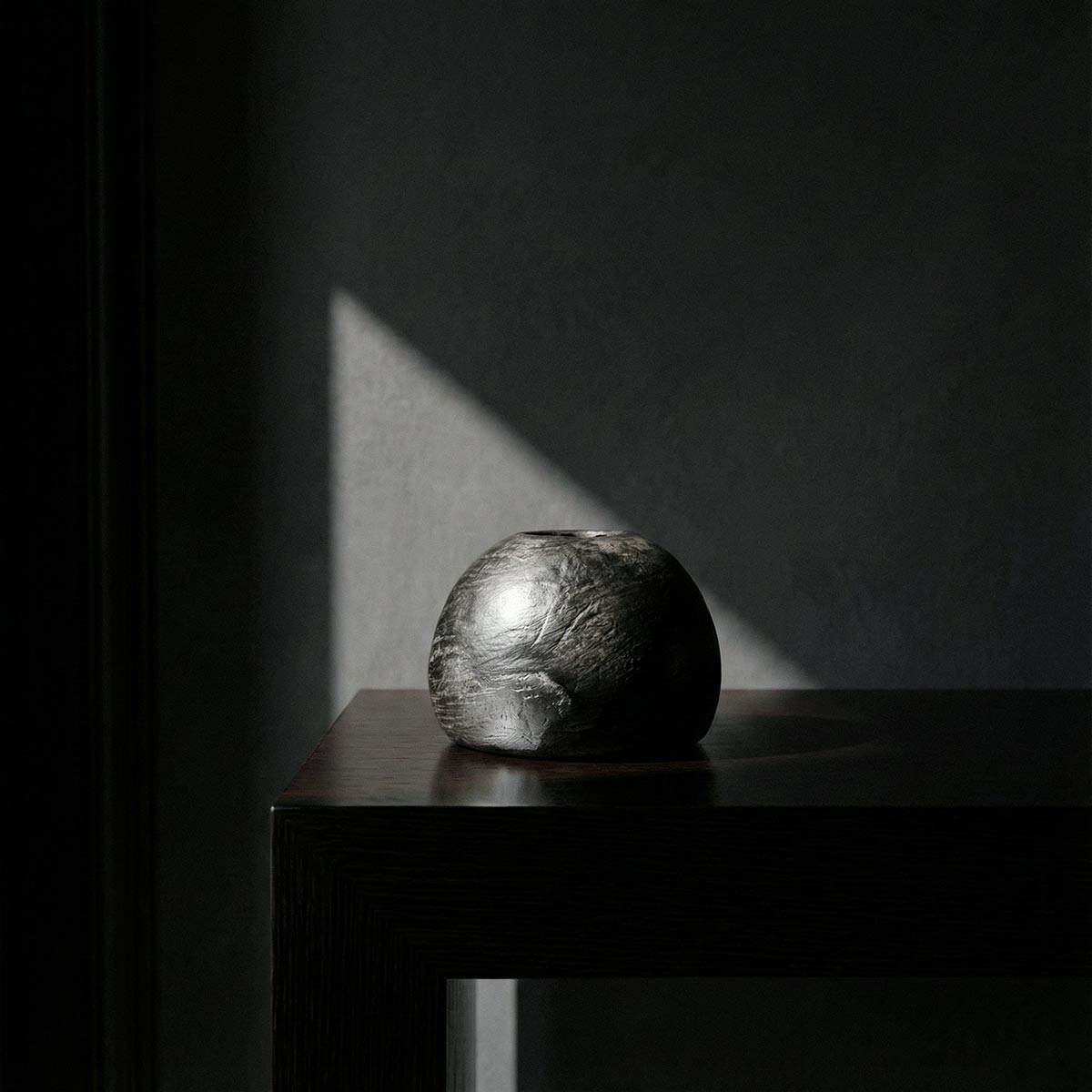 Scultura artistica sfera ceramica nera Najed con illuminazione drammatica