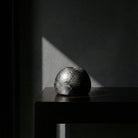 Scultura artistica sfera ceramica nera Najed con illuminazione drammatica