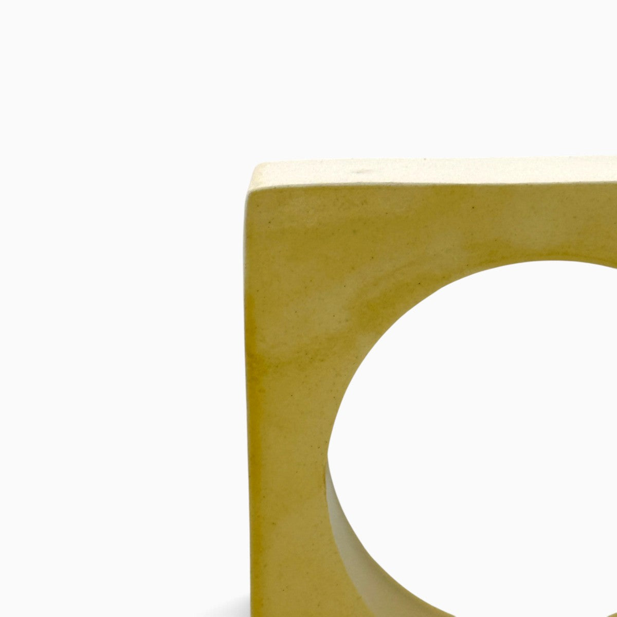 Vista tre quarti della scultura geometrica Soglia Solare in ceramica smaltata giallo ocra