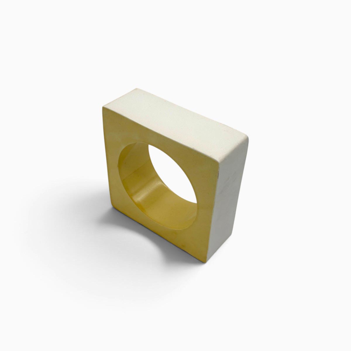 Vista tre quarti della scultura geometrica Soglia Solare in ceramica smaltata giallo ocra