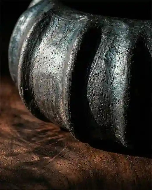 Dettaglio vaso scultura in ceramica nera artigianale con texture materica e design organico unico.