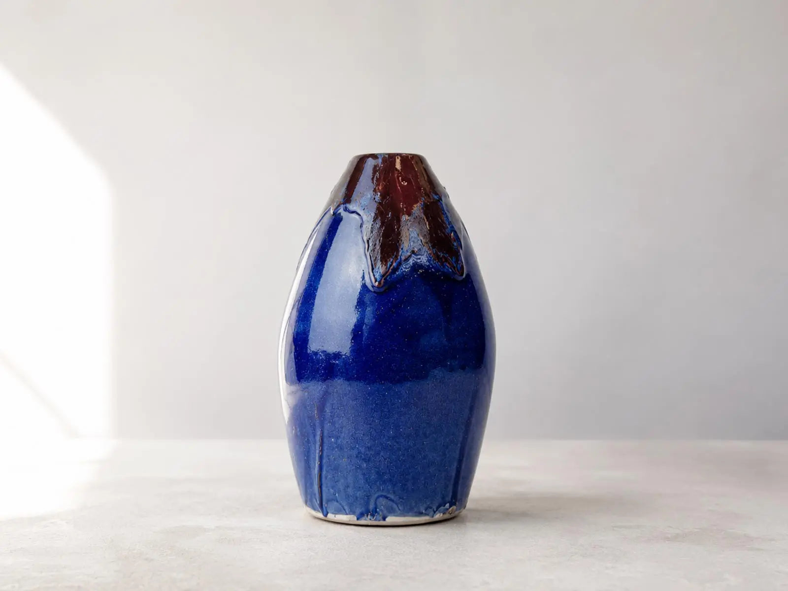 vaso artigianale blu prodfondo con striature rosse, su piano in pietra pronto per essere pulito delicatamente con un panno