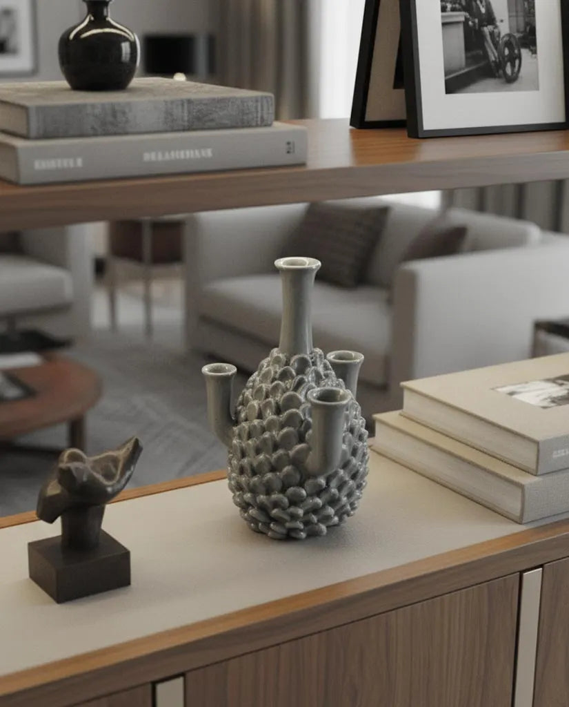 vaso artigianale in ceramica color ottanio appoggiato su una credenza di design in legno di noce canaletto e piano in pelle 