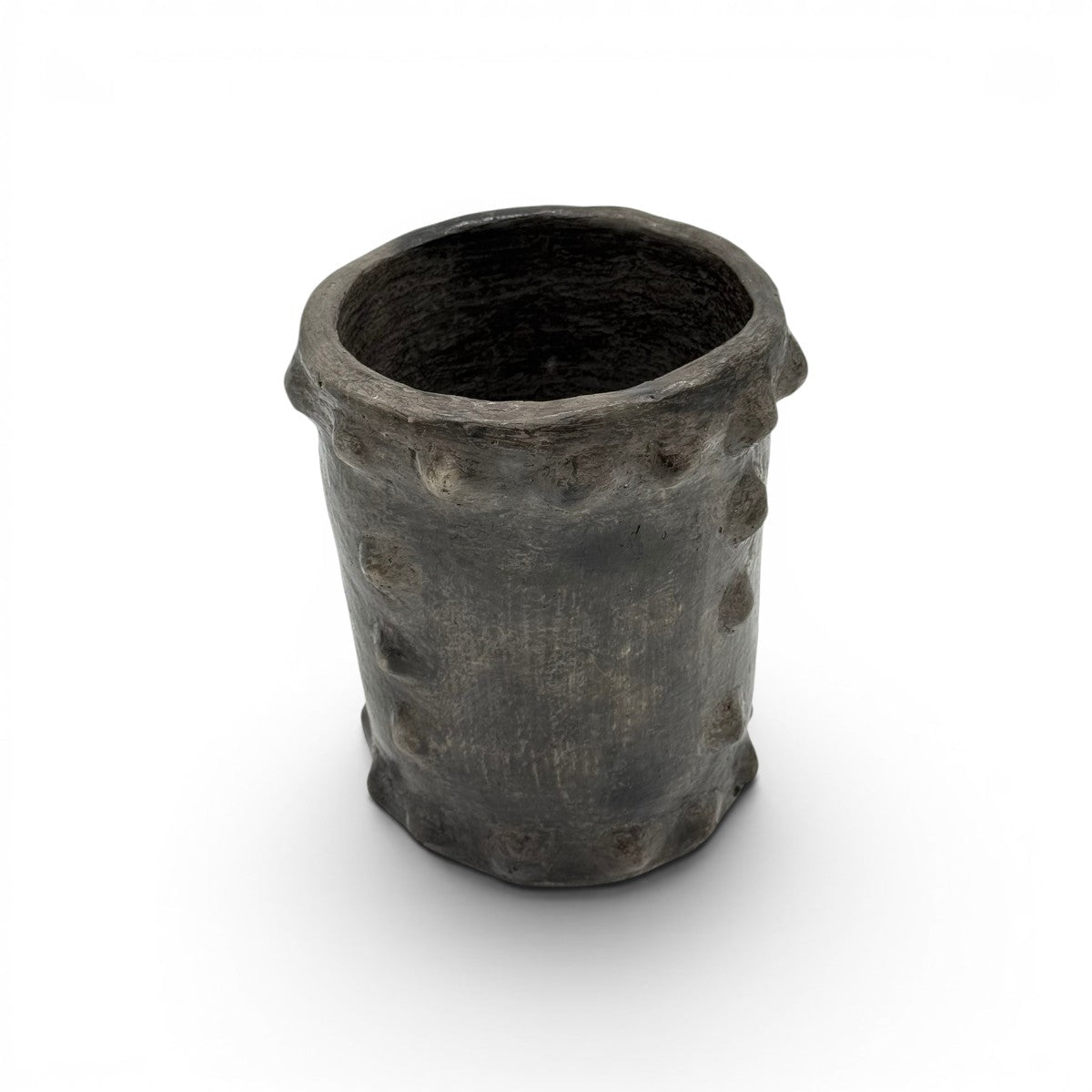 Il vaso scultoreo cilindrico esposto come accento di design espresso su un tavolo da caffè minimalista.
