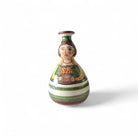 Primo piano del volto gentile e sorridente della Pupetta Fiorita in maiolica.