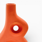 Vaso artistico arancione forma astratta curva su sfondo bianco